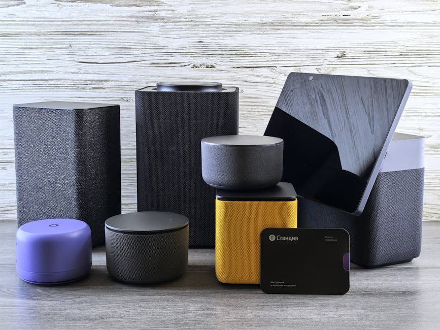 A collection of various smart home speakers and tablet displayed on a wooden surface.