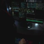 Dark room setup with code displayed on PC monitors highlighting cybersecurity themes.