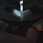 Two people typing on RGB keyboards with code on screens, indicating a cybersecurity environment.